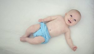 baby in blue bottoms lying on white surface