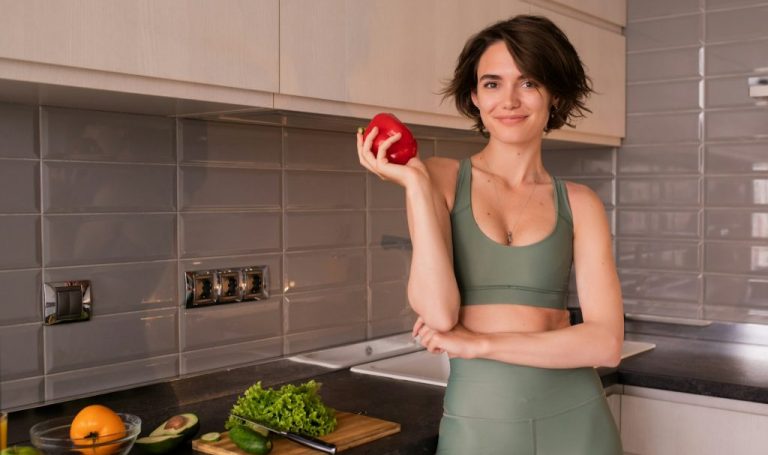 a woman standing in a kitchen holding an apple