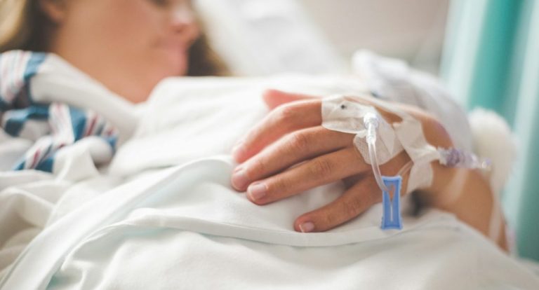 a woman laying in a hospital bed with an iv in her hand