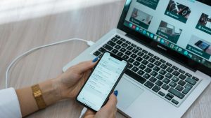 a person using a cell phone while sitting in front of a laptop