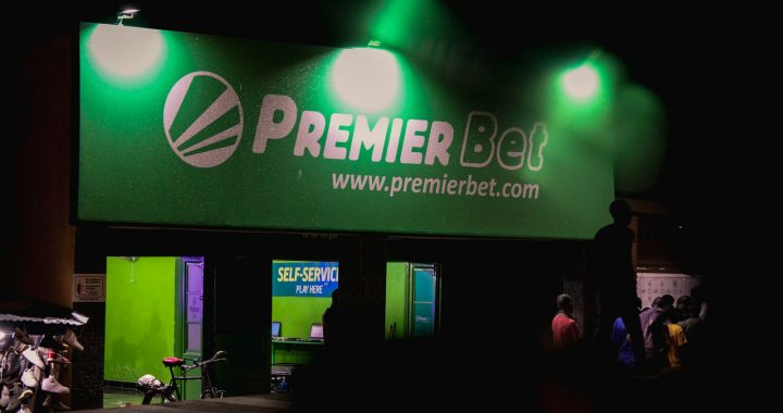 a group of people standing outside of a green building