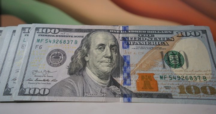 a stack of one hundred dollar bills sitting on top of a table