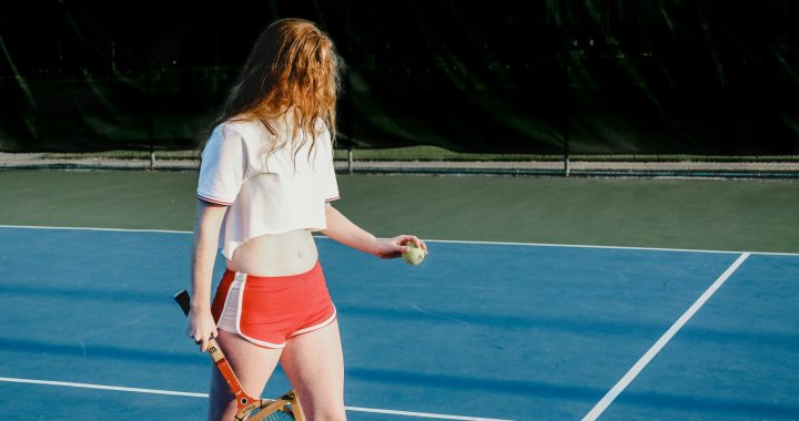 woman in white crop top and red and white dolphin shorts holding green ball and rocket