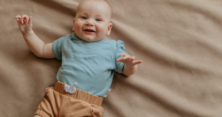 baby in blue shirt and brown shorts lying on brown textile