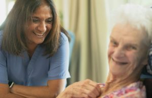 Nurse smiling with elderly patient in room