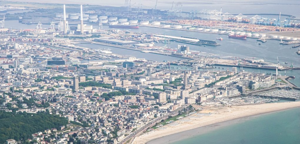 Photo by Sweder Breet Aerial view of a coastal city with a large harbor.
