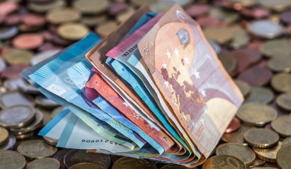 Photo by Willfried Wende A pile of money sitting on top of a pile of coins