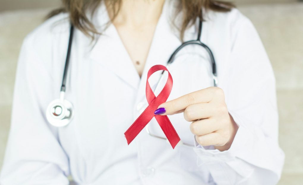 Photo by Bermix Studio a woman in a white shirt holding a red ribbon