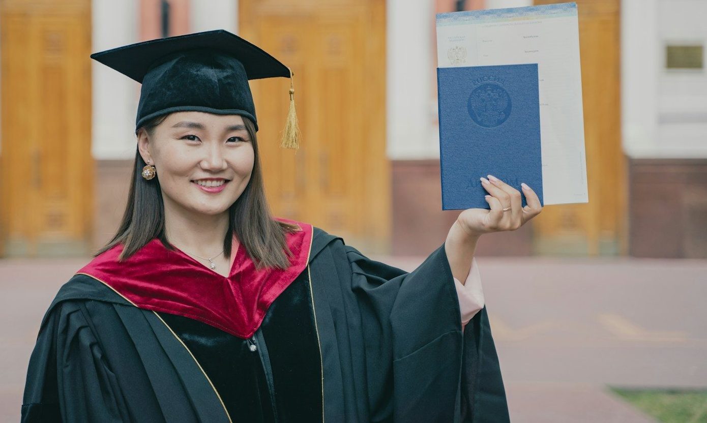 Photo by RUT MIIT a woman in a graduation cap and gown holding a diploma